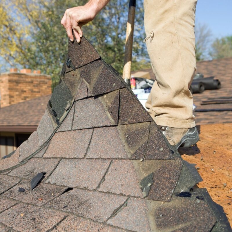 A roofer replacing old shingles
